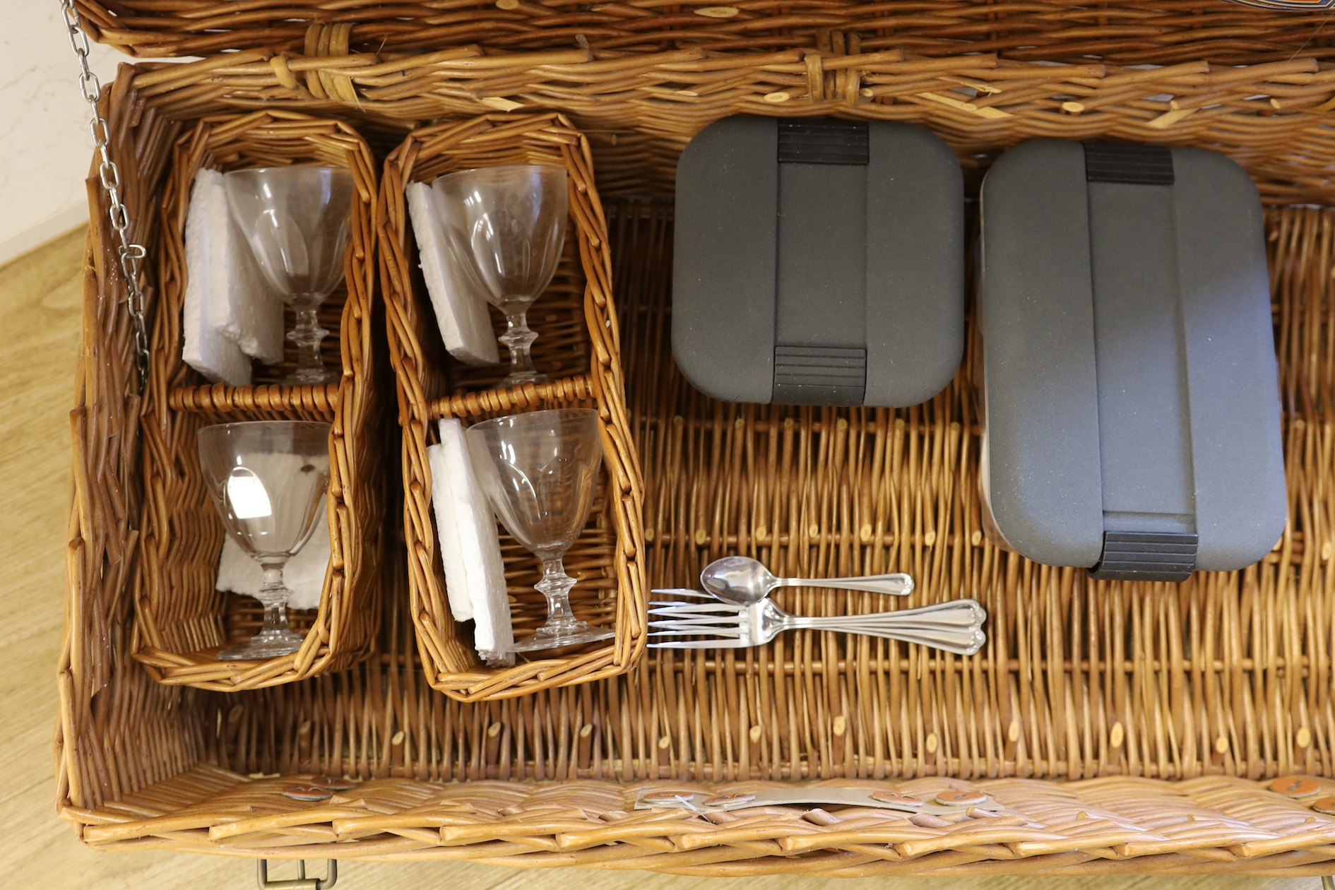 A Harrods wicker picnic hamper for four persons, with Wedgwood plates, cups and saucers, plated cutlery and wine glasses. Condition - good